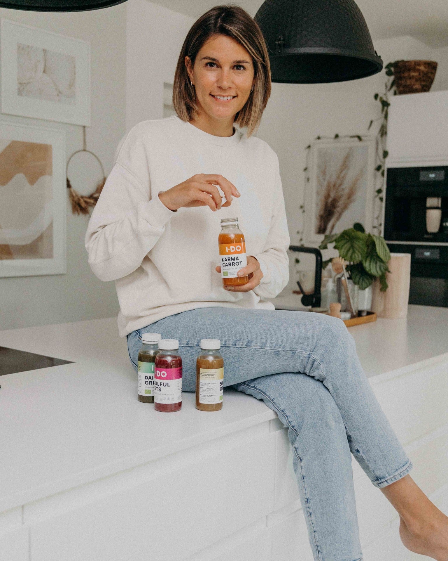 Eine junge Frau sitzt da und genießt einen I·DO-Saft im Rahmen ihrer Bio-Saftkur.