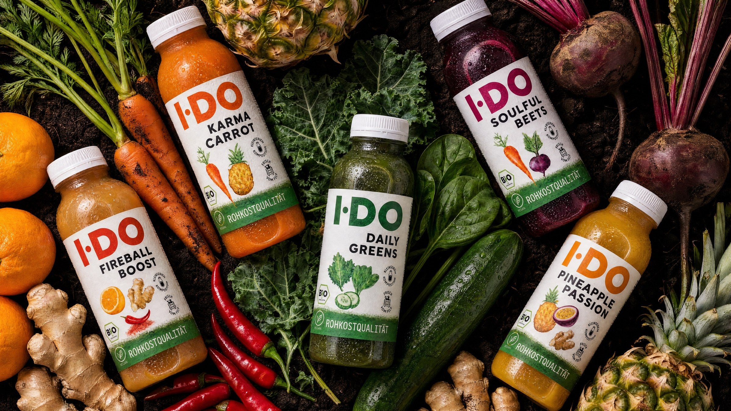 Fünf I·DO Säfte auf rohem Bio-Gemüse: Daily Greens, Karma Carrot, Soulful Beets, Fireball Boost und Pineapple Passion