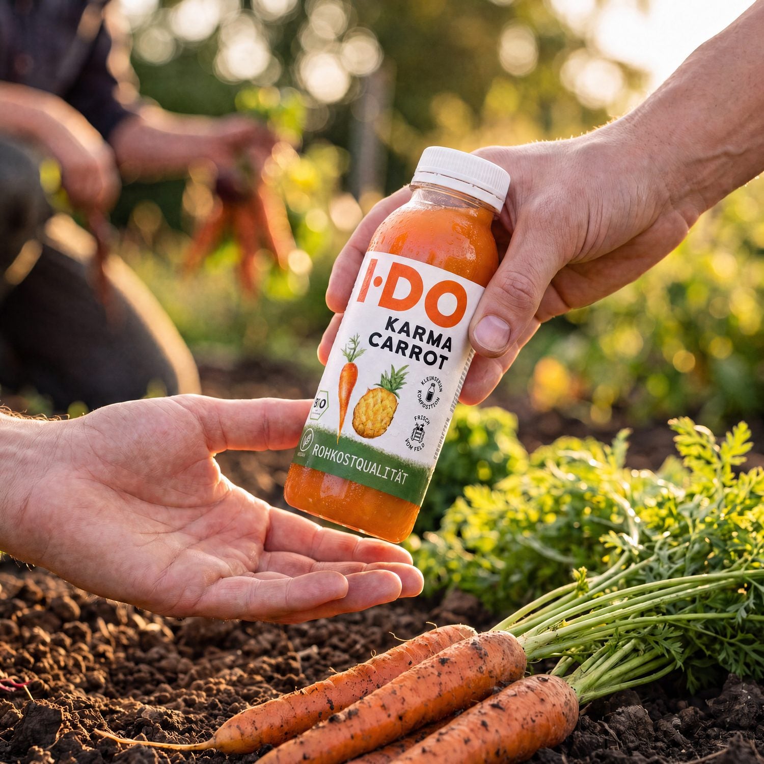 Eine Hand reicht eine I·DO Karma Carrot Flasche an eine offene Hand weiter – Übergabe im goldenen Abendlicht auf dem Feld